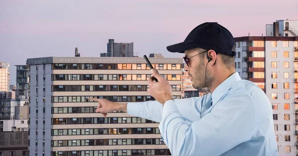 Segurança segurando walkie talkie apontando contra edifícios — Fotografia de Stock