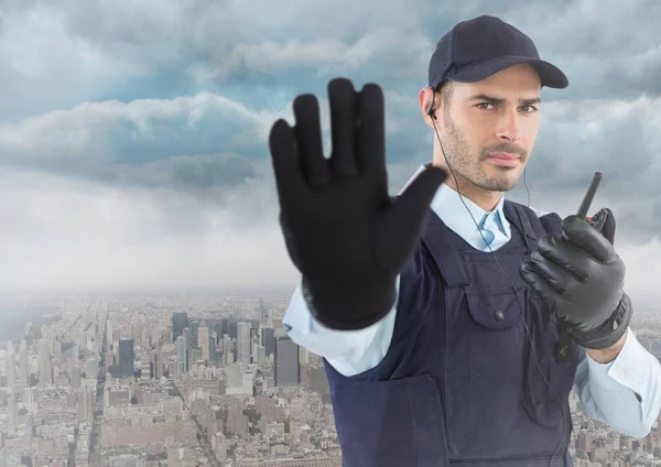 Guarda de segurança com walkie talkie e mão para cima contra skyline e nuvens — Fotografia de Stock