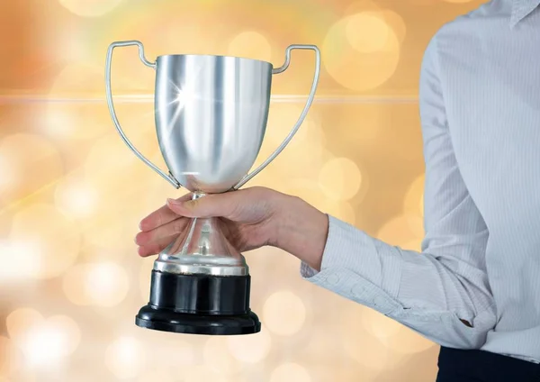 Businesswomen holding a trophy in a gold background — Stock Photo, Image