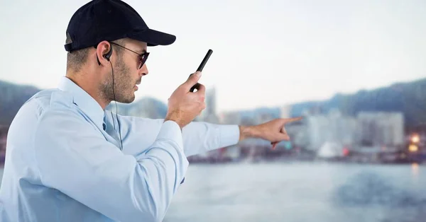 Security guard met walkie talkie wijzen tegen wazig skyline — Stockfoto