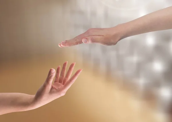 Hands reaching to eachother helping with sparkling light bokeh background — Stock Photo, Image
