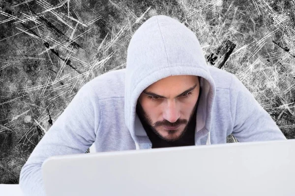Kijkende cyber crimineel is kijken naar het scherm van de laptop tegen een grijze achtergrond — Stockfoto