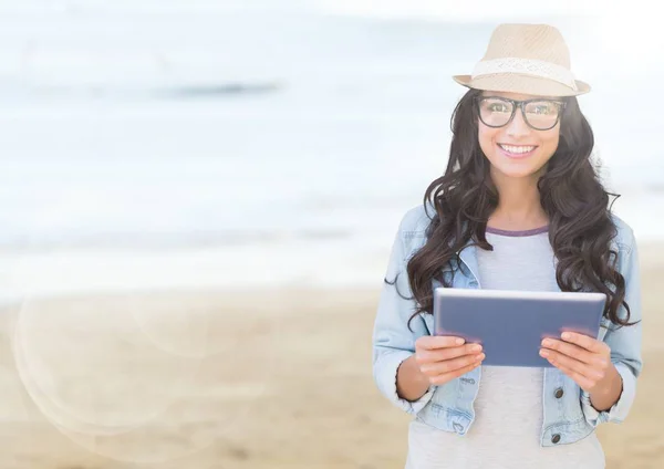 Femme à la mode avec tablette contre plage floue avec fusée éclairante — Photo