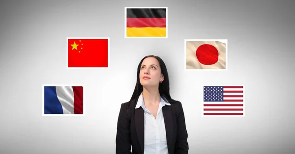 Businesswoman standing by flags against gray background — Stock Photo, Image