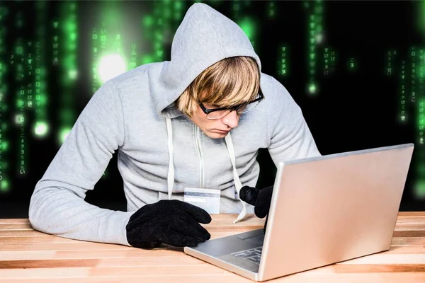 Hacker met behulp van een laptop met een groene en zwarte digitale achtergrond — Stockfoto