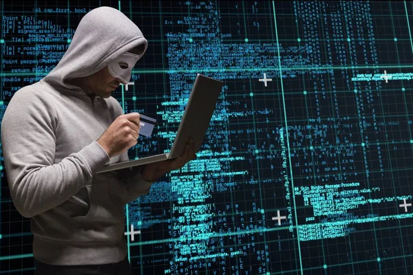 Kyberzločinci drží kreditku a notebooku matice kódu déšť pozadí — Stock fotografie