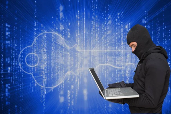 Cyber kriminella bär en huva hacking en laptop mot matris kod bakgrund — Stockfoto