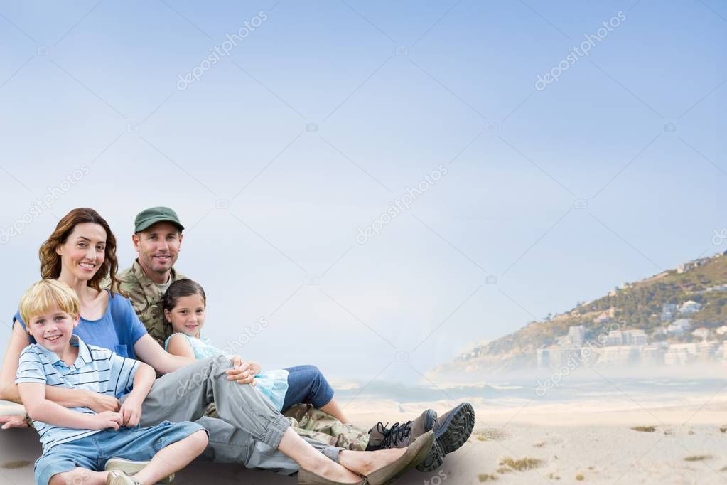 Family sitting on sand against coastline background 