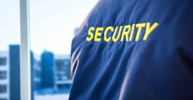 Back of security guard jacket against blurry window showing city clipart