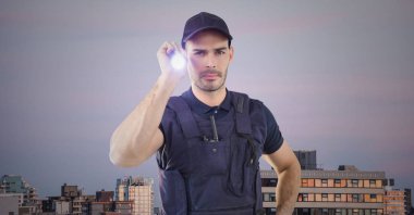 Güvenlik görevlisi binalar ve mor gökyüzü karşı el feneri ile