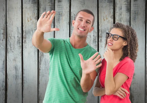 A man showing something to a girl in front of wood wall — Stock Photo, Image
