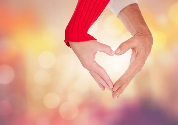 Manos haciendo forma de corazón con luz brillante fondo bokeh — Foto de Stock