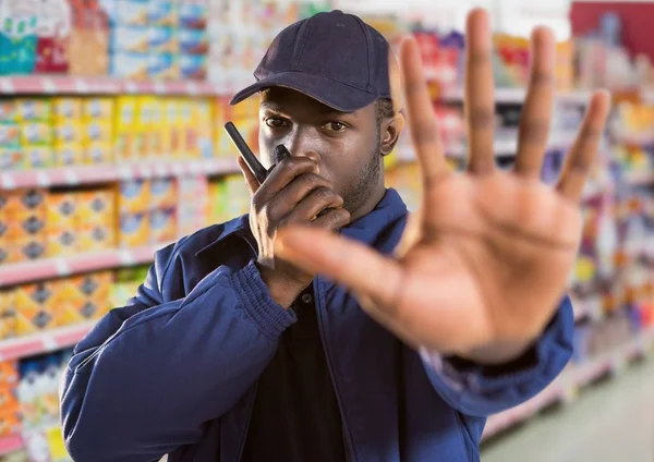 Gardien de sécurité du supermarché disant stop avec sa main (floue) et parler avec le walkie-t — Photo