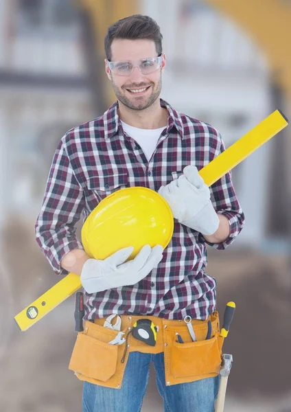 Construction Worker with spirit level in front of construction site — Stock Photo, Image