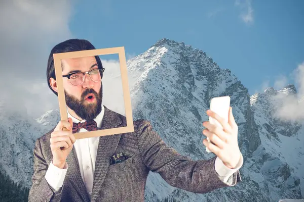 Hombre tomando una selfie con un marco frente a montañas cubiertas de nieve —  Fotos de Stock