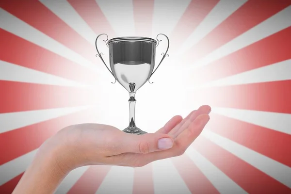 Hand holding trophy against linear red and white background — Stock Photo, Image