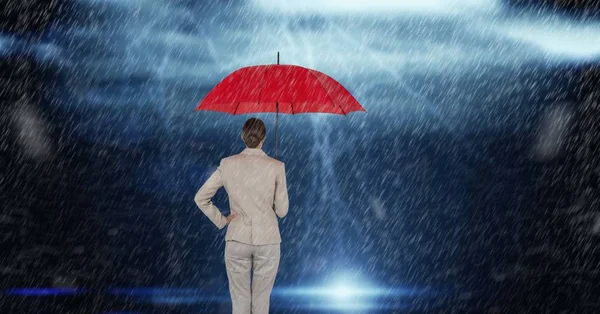 Вид сзади на деловую женщину с красным зонтиком, стоящим под дождем — стоковое фото