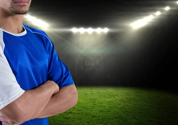 Ποδοσφαιριστή με τα χέρια του διπλωμένα και με μπλε t-shirt στο πεδίο τη νύχτα με τα φώτα — Φωτογραφία Αρχείου