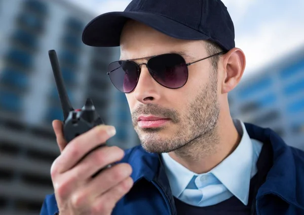 Guardia de seguridad serio con gafas y walkie-talkie con un fondo borroso del edificio —  Fotos de Stock