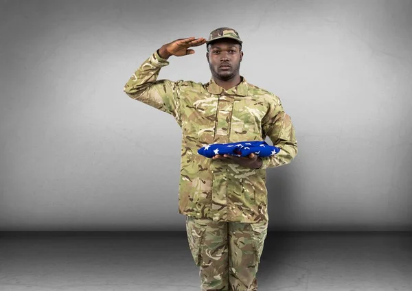 Soldier saluting and with flag in the other hand. concrete room — Stock Photo, Image