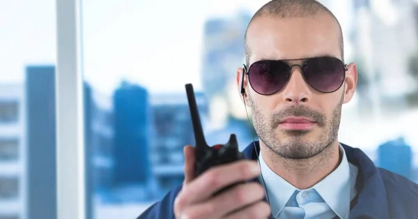 Security guard met walkie talkie tegen wazig venster weergegeven: stad — Stockfoto