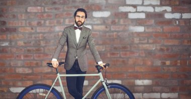 Kırmızı taş duvar önünde bir bisiklet adamla hipster yansıtan