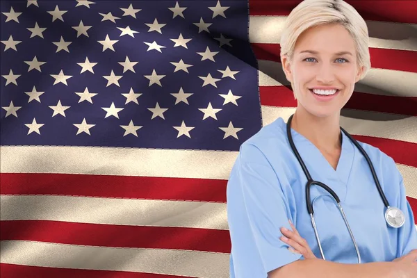 Medico con braccio incrociato contro bandiera americana — Foto Stock