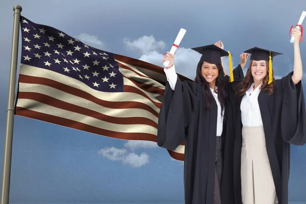Studenten het dragen van een badjas huren Toon diploma tegenover de Amerikaanse vlag tegen hemelachtergrond — Stockfoto