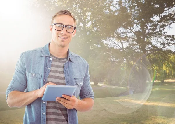 Homme avec tablette contre parc ensoleillé avec fusée éclairante — Photo