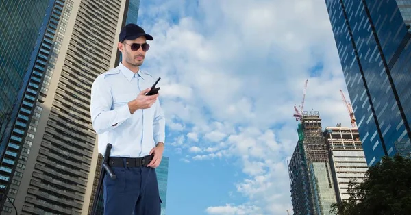 Security guard holding walkie talkie terwijl je tegen gebouwen — Stockfoto