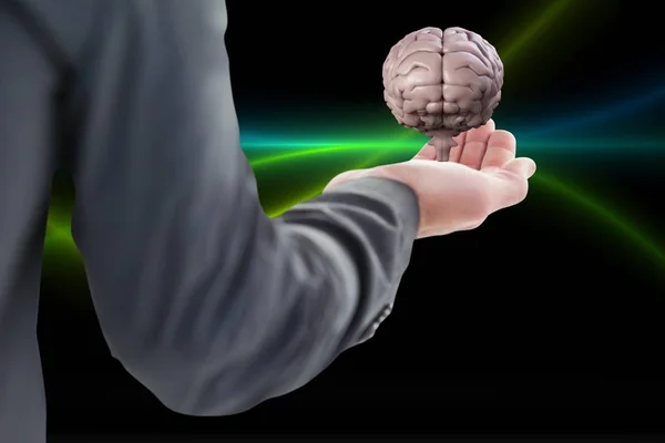 Zakenman die houdt een brein op zijn hand tegen zwarte achtergrond — Stockfoto
