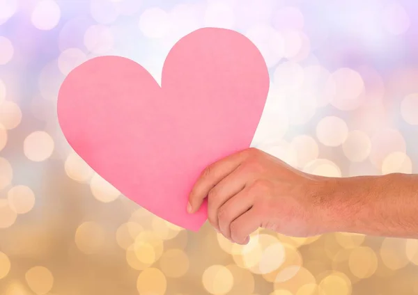Hand hält ausgeschnittenes Herz mit funkelndem Licht Bokeh Hintergrund — Stockfoto