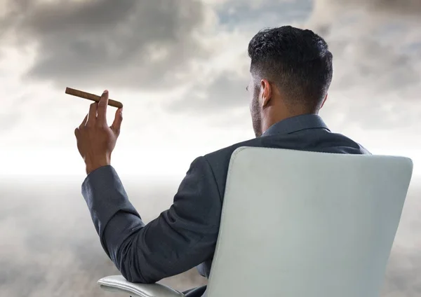 Назад бізнесмен палить сигару і дивиться на хмари — стокове фото