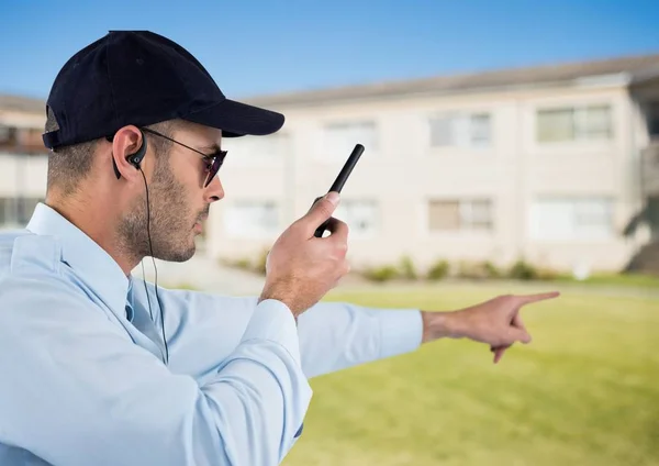 Security guard holding walkie talkie en gebaren terwijl staande op veld — Stockfoto