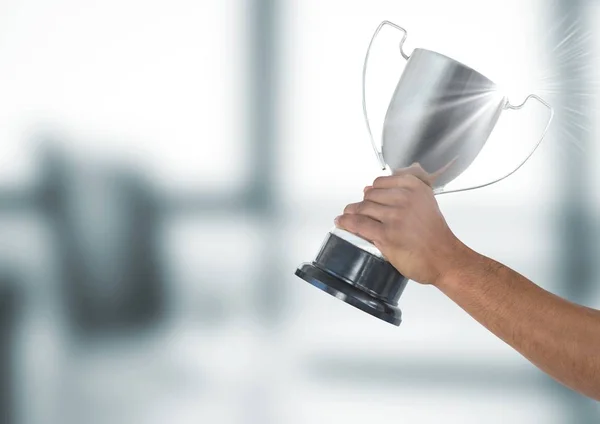 Hand holding trophy against defocused background — Stock Photo, Image