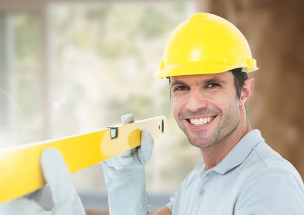 Construction Worker with spirit level in front of construction site — Stock Photo, Image