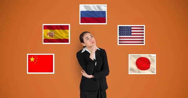 Tankeväckande affärskvinna stående av flaggor mot orange bakgrund — Stockfoto