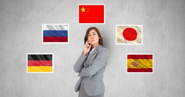 Businesswoman thinking while standing by flags against gray background — Stock Photo, Image