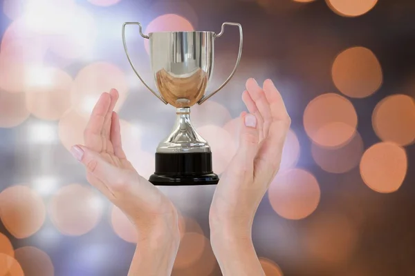 Manos sosteniendo trofeo contra fondo naranja brillante — Foto de Stock