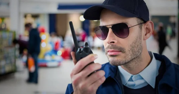 Security guard met walkie talkie tegen wazig winkelcentrum — Stockfoto