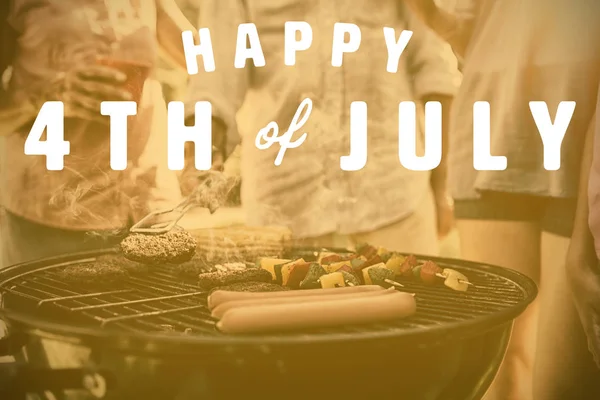 Gelukkige 4 van juli tekst tegen familie met barbecue — Stockfoto