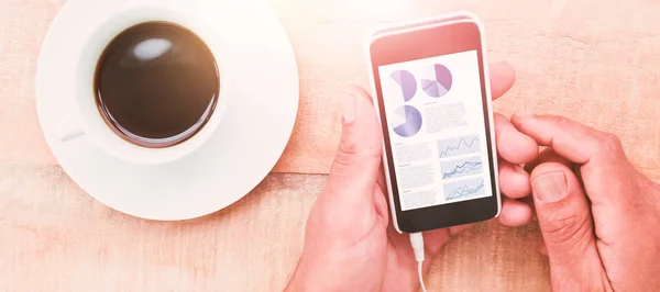 Manos sosteniendo el teléfono inteligente junto a la taza de café — Foto de Stock