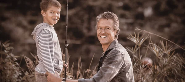 Vader en zoon met hengel op veld — Stockfoto