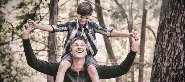 Fröhlicher Vater trägt Sohn auf Schultern im Wald — Stockfoto
