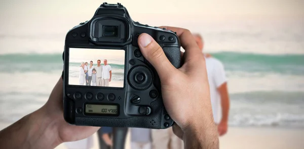 Immagine ritagliata di mani che tengono la macchina fotografica con grande famiglia sullo schermo — Foto Stock