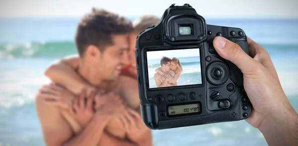Handen met camera met mooie paar op strand op scherm — Stockfoto