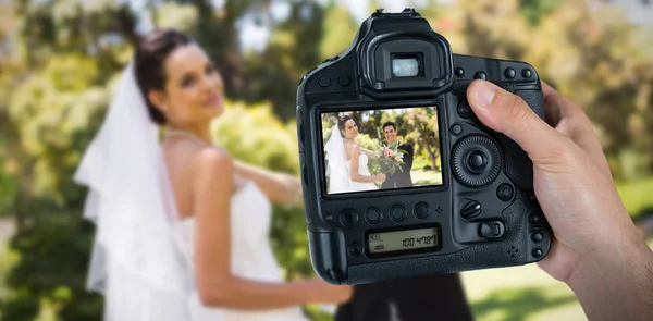 Imagen compuesta de la mano recortada del fotógrafo sosteniendo la cámara — Foto de Stock