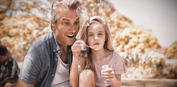 Père et fille soufflant baguette à bulle au pique-nique dans le parc — Photo