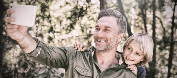 Lachende vader en zoon selfie nemen in bos — Stockfoto