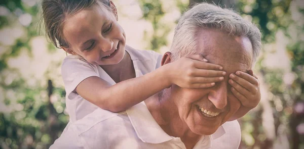 Playful girl covering grandfather eyes — Stock Photo, Image